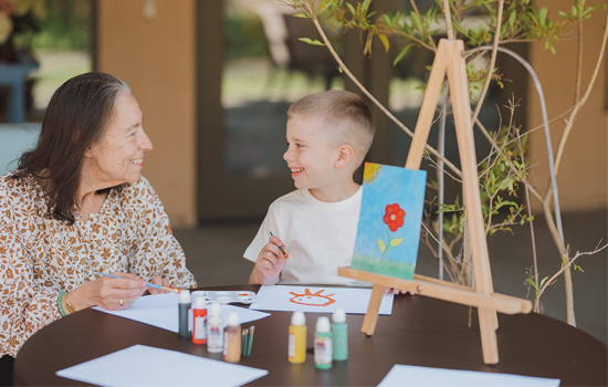 Resident paints with grandson at The Gardens of Sun City Assisted Living in Sun City, AZ