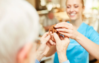Nursing woman helps senior with dementia patience with a wooden puzzle